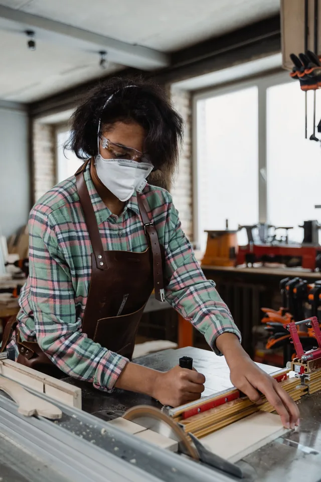 Fachkraft mit Schutzbrille bei der Holzarbeit in einer Werkstatt