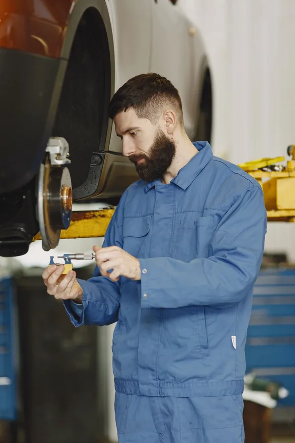 Ein Automechaniker prüft eine Bremse mit einem Messschieber.
